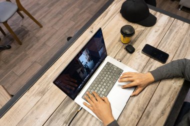 Ofiste dizüstü bilgisayarda çalışan genç adam.