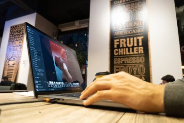 Kahve dükkanında dizüstü bilgisayar kullanan adam.