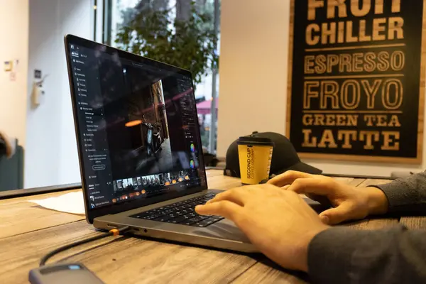 Kafede dizüstü bilgisayarla çalışan genç adam.