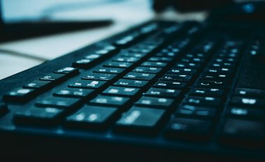 Siyah bir arkaplanda batan güneşin ışığı olan bir klavyenin yakın çekim görüntüsü.