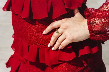 Şehir parkında poz veren şık ve güzel, kırmızı elbiseli beyaz bir kadın. Bakü, Azerbaycan. 28.08.2025.