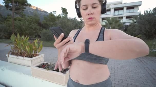 Νέοι Συν Μέγεθος Γυναίκα Χρησιμοποιώντας Tracker Γυμναστήριο Ενώ Τζόκινγκ Εξωτερικούς — Αρχείο Βίντεο