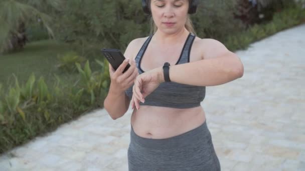 Fiatal Plusz Méret Használ Fitness Tracker Miközben Kocog Szabadban — Stock videók