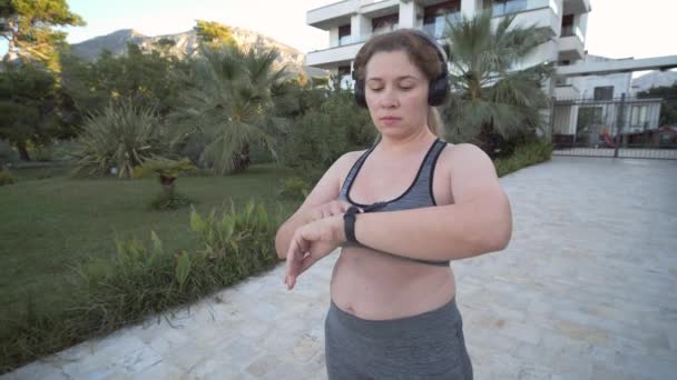 Jovem Mulher Size Usando Rastreador Fitness Enquanto Corre Livre — Vídeo de Stock