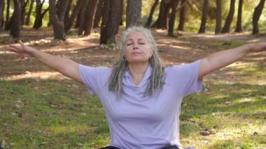 Kafkasyalı, spor kıyafetli olgun kadın portresi. Açık hava parkındaki spor minderinde meditasyon yaparken zen hissi veriyor. Sağlıklı aktif yaşam biçimi