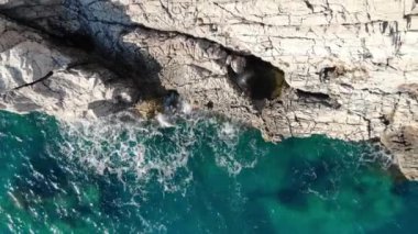 Dalgalar kayalara çarpar. Mavi deniz güneşli bir günde