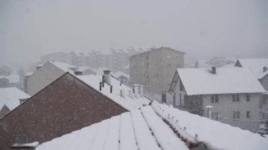 Çatıları olan şehrin üzerinde şiddetli kar yağışı