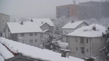 Çatıları olan şehrin üzerinde şiddetli kar yağışı