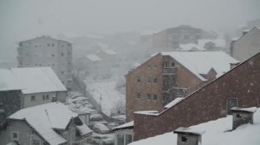 Çatıları olan şehrin üzerinde şiddetli kar yağışı