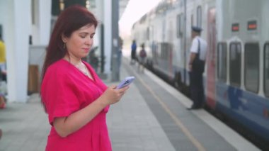 Tren gelene kadar akıllı telefon kullanan bir kadın. İleti iletileri e- posta ya da tren tarifesi kontrol ediliyor
