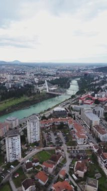 Tatil ve seyahat konsepti. Podgorica Karadağ: Moraca nehri ve tarihi eser olan Millennium köprüsü de dahil olmak üzere şehir merkezinin üzerindeki güzel günbatımı. Hava görünümü.