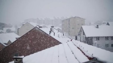Çatıları olan şehrin üzerinde şiddetli kar yağışı