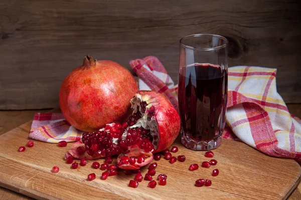 Sammansättning Mogna Röda Granatäpplen Och Glas Färsk Rostig Juice Trä Stockfoto