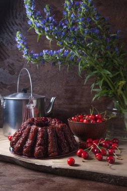 Koyu renk ahşap arka planda kompozisyon - tatlı kirazlı lezzetli çikolatalı pasta, kirazlı kirazlı kiraz kasesi, kaliteli çaydanlık ve güzel mavi çiçekli cam kavanoz.