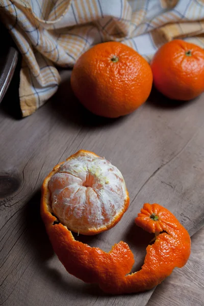 stock image Several of whole fresh orange mandarine or oranges, tangerines, clementines, citrus fruits and one fruit is half peeled on wooden boar