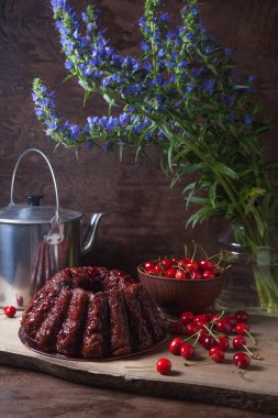 Koyu renk ahşap arka planda kompozisyon - tatlı kirazlı lezzetli çikolatalı pasta, kirazlı kirazlı kiraz kasesi, kaliteli çaydanlık ve güzel mavi çiçekli cam kavanoz.