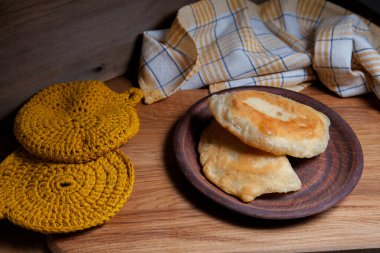 Ahşap masada iki ayrı kızarmış etli kil tabak. Tatar geleneksel turtaları.