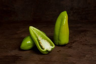 Tam ve yarım porsiyon yeşil dolmalık biber (capsicum) tatlı dolmalık biber olarak bilinir, eski ahşap arka planda kırmızı biber. Sebze koleksiyonu.