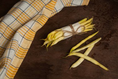 Bir sürü ve ahşap zemin üzerinde sarı mutfak havlusu olan bir sürü ham sarı haricot. Fransız fasulyesi ya da Hindistan 'dan String fasulyesi olarak da bilinir. Sebze koleksiyonu.