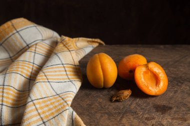 İki tam ve yarım kayısı meyvesi eski ahşap arka planda