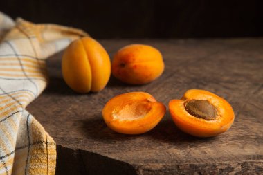 İki tam ve yarım kayısı meyvesi eski ahşap arka planda