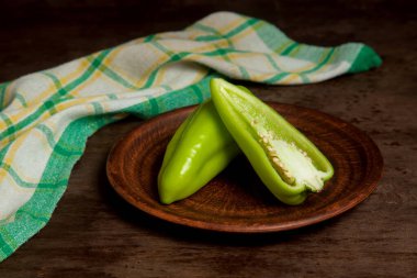Kaliteli ahşap arka planda tatlı dolmalık biber, paprika ve yeşil mutfak havlusu olarak bilinen yeşil dolma biber (capsicum) dolu kil tabağı. Sebze koleksiyonu.