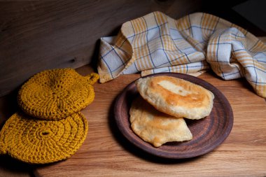 Ahşap masada iki ayrı kızarmış etli kil tabak. Tatar geleneksel turtaları.