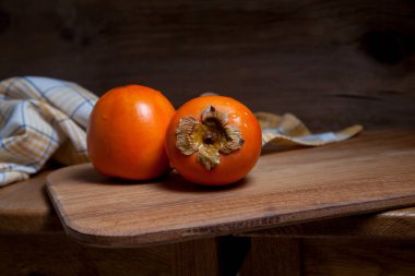 Lezzetli taze hurma meyveleri ahşap zeminde yenmeye hazır.