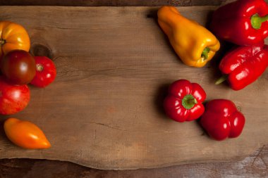 Sebze arkaplan resmi. Farklı şekil ve renkte olgun sulu domatesler ve eski ahşap arka planda dolmalık biber.
