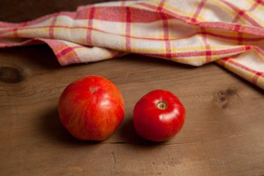 Ahşap arka planda kırmızı havluyla sulu kırmızı domatesler. Sebze koleksiyonu