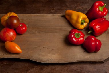 Sebze arkaplan resmi. Farklı şekil ve renkte olgun sulu domatesler ve eski ahşap arka planda dolmalık biber.