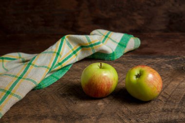 Ahşap arka planda iki yeşil elma ve yeşil mutfak havlusu.