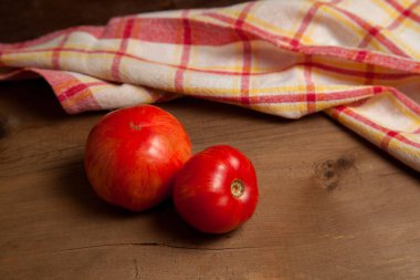 Ahşap arka planda kırmızı havluyla sulu kırmızı domatesler. Sebze koleksiyonu