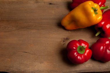 Sebze arkaplan resmi. Farklı şekillerde ve renkte olgun sulu dolmalık biberler eski ahşap arka planda.
