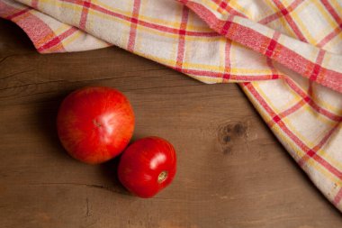 Ahşap arka planda kırmızı havluyla sulu kırmızı domatesler. Sebze koleksiyonu