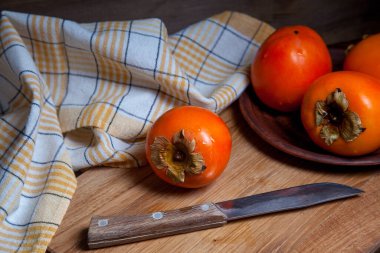 Lezzetli taze hurma meyveleri ve ahşap zemin üzerinde eski model bıçakla yenmeye hazır.