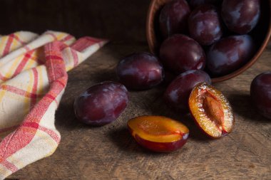 Sulu yaz eriği meyvesi. Kaliteli ahşap arka planda bir sürü olgun tatlı erik. Arka planda erikler olan kil plaka