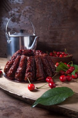 Koyu renk ahşap arka planda kompozisyon - tatlı kirazlı lezzetli çikolatalı pasta, eski moda çaydanlık, kiraz meyveli kiraz kasesi ve kiraz ağacı yapraklı kiraz.