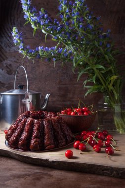 Koyu renk ahşap arka planda kompozisyon - tatlı kirazlı lezzetli çikolatalı pasta, kirazlı kirazlı kiraz kasesi, kaliteli çaydanlık ve güzel mavi çiçekli cam kavanoz.
