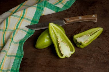 Yeşil dolmalık biber (capsicum), tatlı dolmalık biber, yeşil mutfak havlusuyla kırmızı biber ve klasik ahşap arka planda bıçak olarak bilinir. Sebze koleksiyonu.