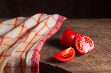 Eski ahşap arka planda olgun sulu pembe domates ve kırmızı havlu kes. Sebze koleksiyonu