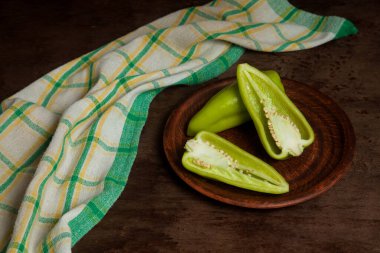 Kaliteli ahşap arka planda tatlı dolmalık biber, paprika ve yeşil mutfak havlusu olarak bilinen yeşil dolma biber (capsicum) dolu kil tabağı. Sebze koleksiyonu.
