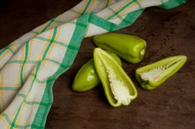 İki tam ve yarım yeşil dolmalık biber (capsicum) tatlı dolmalık biber olarak bilinir, yeşil mutfak havlusu ve eski ahşap arka plan. Sebze koleksiyonu.