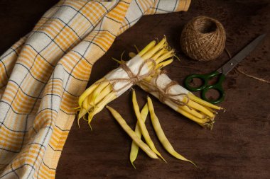 İki deste ve sarı mutfak havlusu, makas ve ahşap zemin üzerinde iplik yumağı olan bir sürü ham sarı kayısı. Fransız fasulyesi ya da Hindistan 'dan String fasulyesi olarak da bilinir. Sebze koleksiyonu.