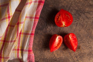 Eski ahşap arka planda olgun sulu pembe domates ve kırmızı havlu kes. Sebze koleksiyonu