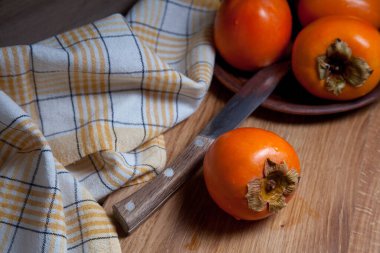 Lezzetli taze hurma meyveleri ve ahşap zemin üzerinde eski model bıçakla yenmeye hazır.