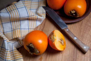 Lezzetli olgun meyveler, yarısı ve dilimlenmiş meyveler ahşap arka planda klasik bıçakla yenmeye hazır.