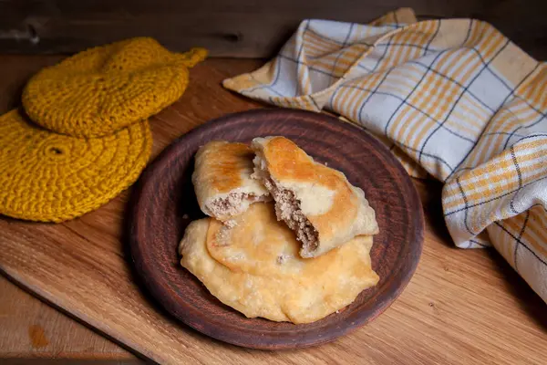 Ahşap masada iki ayrı kızarmış etli kil tabak. Fast food akşam yemeği kompozisyonu - iki turta ile vintage ahşap arka planda domuz pastası.