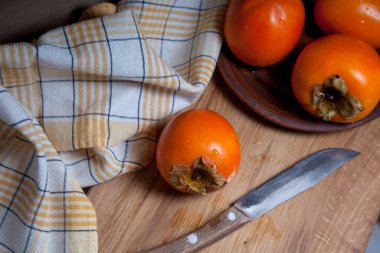 Lezzetli taze hurma meyveleri ve ahşap zemin üzerinde eski model bıçakla yenmeye hazır.