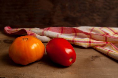 Kırmızı havluyla eski ahşap arka planda olgun kırmızı ve sarı domatesler. Sebze koleksiyonu